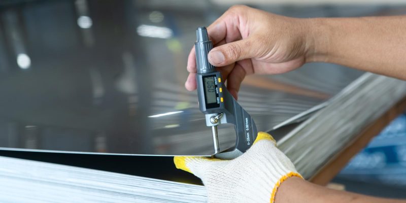 The photo shows how to measure how thick of the metal sheet by using digital thickness gauge.